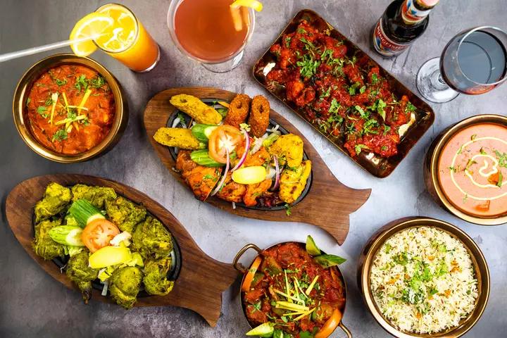 a table topped with plates of Indian food and drinks
